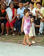 Con menos de dos años y llevada de la mano por Daniela, la pequeña Sofia fue la menor de los participantes. Ambas lucen batas diseñadas y realizadas una, en algodón entintado, y otra, tejida a crochet por María Elena Pérez Cruz, quien aparece sentada en el fondo vestida de rojo.